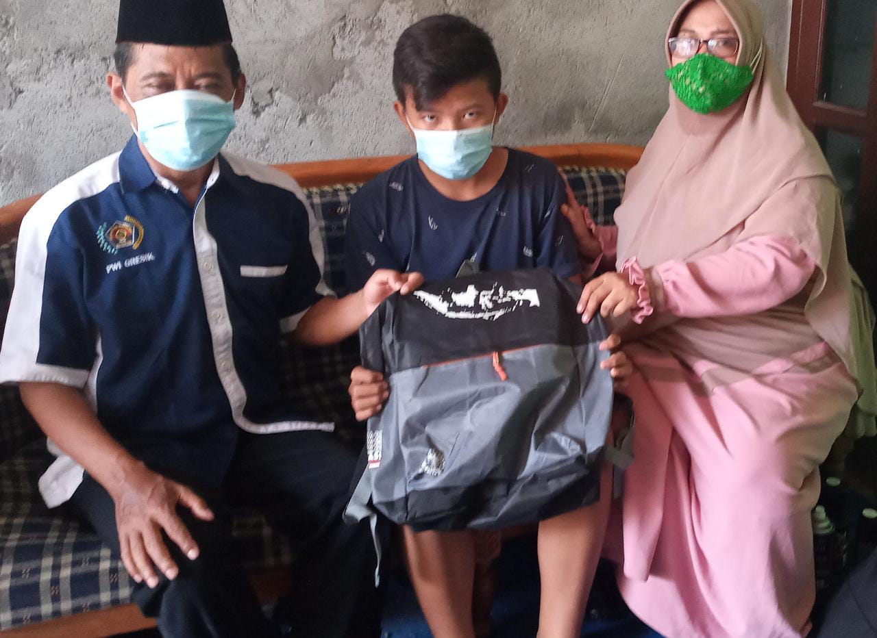 PWI Gresik Beri Tas Sekolah Bagi Yatim Non Panti 1 anak yatim non panti menerima tas buat sekolah dari salah seorang pengurus PWI