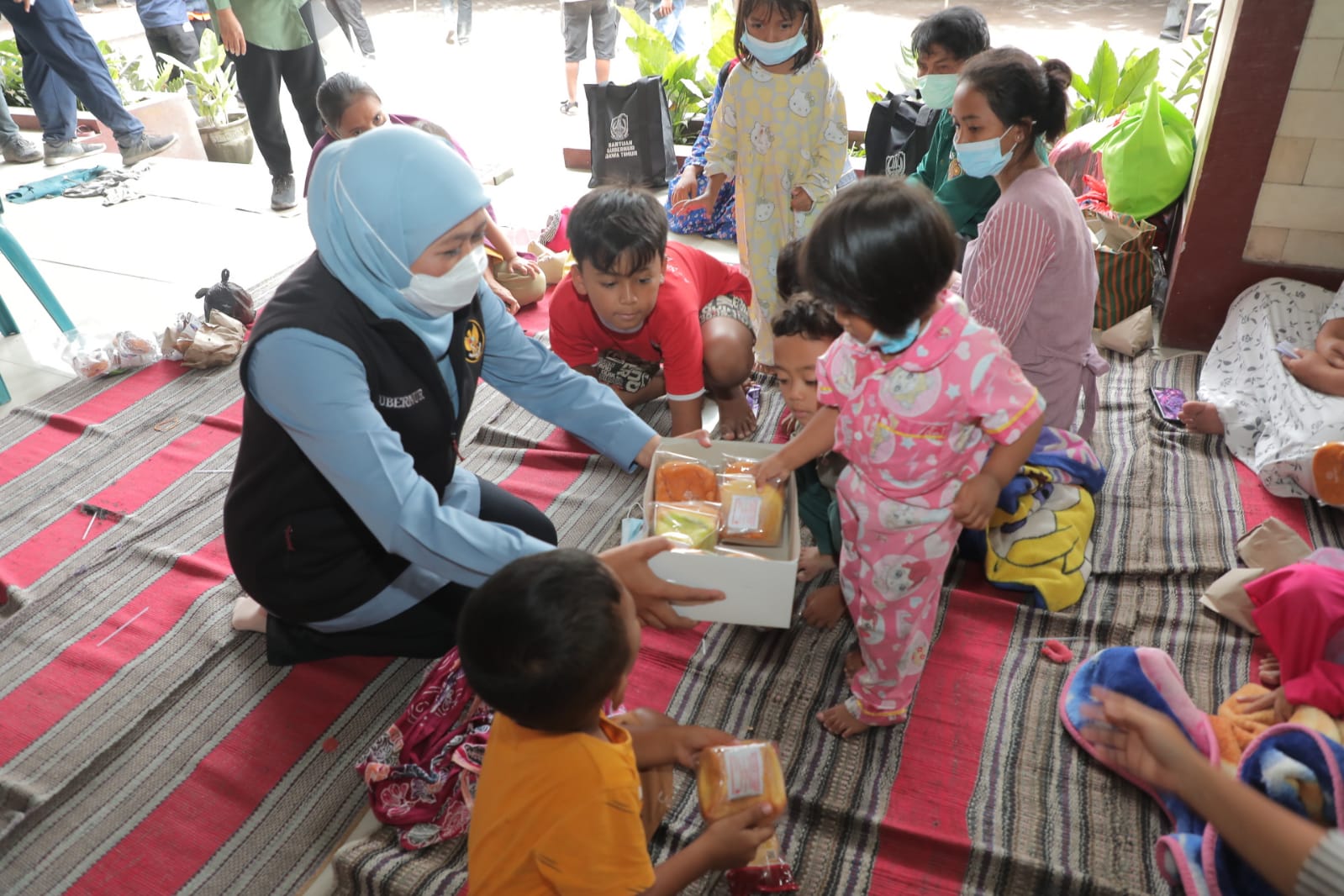 Teks foto: Gubernur Khofifah meninjau pengungsian warga terdampak erupsi gunung Semeru sambil menyerahkan bantuan dan menghibur anak- anak. (Ist)
