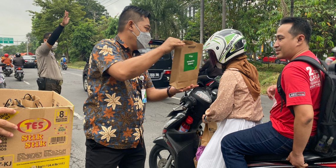 Rudi Susanto, Kepala Kantor BPJS Ketenagakerjaan Surabaya Rungkut saat membagikan takjil kepada pengguna jalan jelang berbuka puasa di Jl. Raya Jemursari, Surabaya, Kamis (21/4/2022) sore. (Ist)