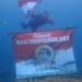Salah seorang anggota Satpolair saat mengibarkan Bendera Merah Putih di bawah laut