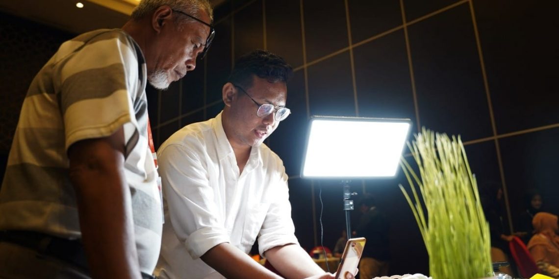 Instruktur dari UMG, Zulfikar (kanan), mengajarkan praktik cara foto produk yang benar pada Kamaluddin, pengelola telur asin ROMO Gresik, di Hotel Aston, Gresik, Jum'at (15/7/2022). (ist)