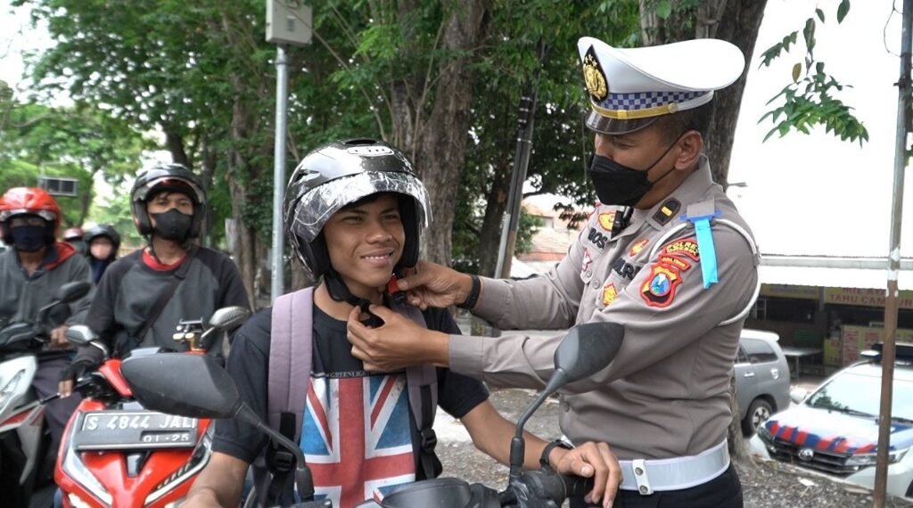 Petugas Satlantas Polres Gresik saat membagikan Helm SNI secara gratis pada pengendara sepeda motor