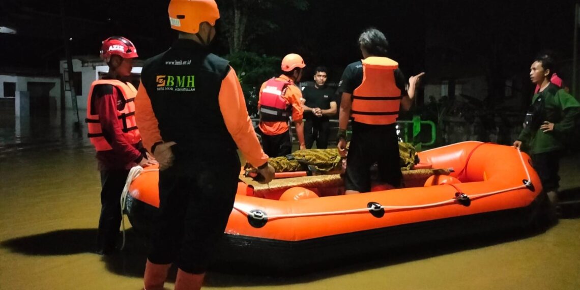 Dengan menggunakan perahu karet, para relawan BMH menyerahkan bantuan ke rumah warga terdampak banjir di Blitar. (ist)