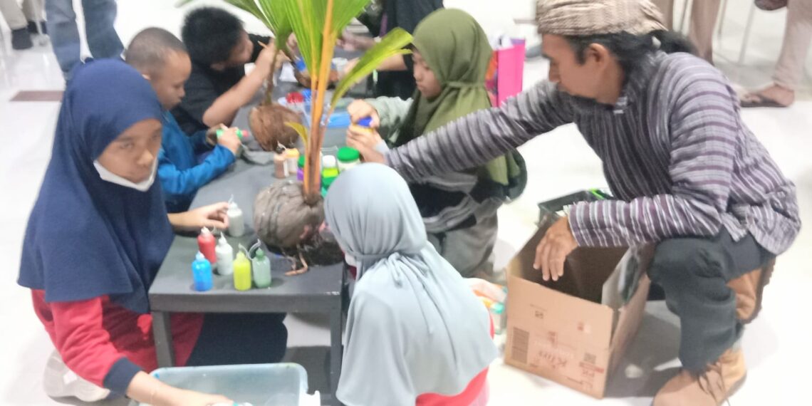 Ustadz Arik mendampingi siswanya melukis diatas tunas kelapa.