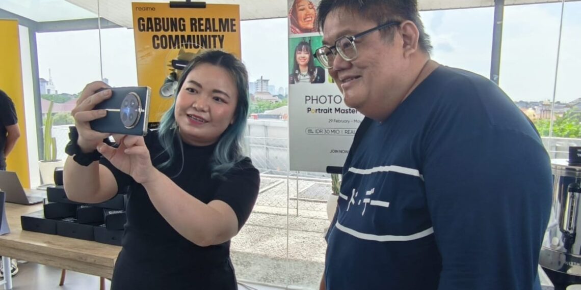 Krisva Angnieszca PR Lead, realme Indonesia menunjukkan fitur HP realme 12 Series 5G dengan lensa telefoto periskop ke pengamat seluler Herry SW di Surabaya. (foto2: ist)