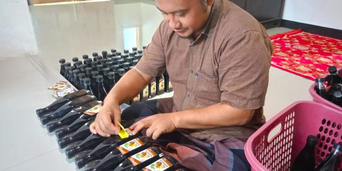 Ahmad Soffa, UMKM minuman rasa buah kawista memberi label pada botol sirop di rumah produksi Sirop Kawista Sonaya di Desa Sumbergirang, Kec. Lasem, Rembang, Jawa Tengah. (foto: ist)