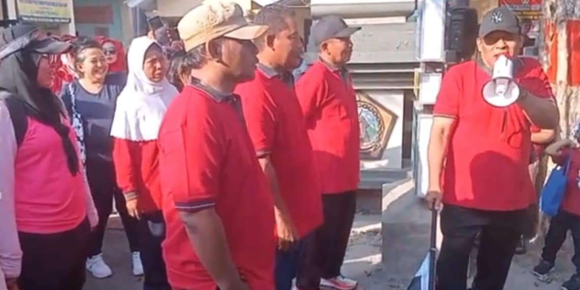 Kades Hullaan Hamdani Widianto saat mengibarkan bendera start pada acara jalan sehat memperingati HUT RI ke-79.