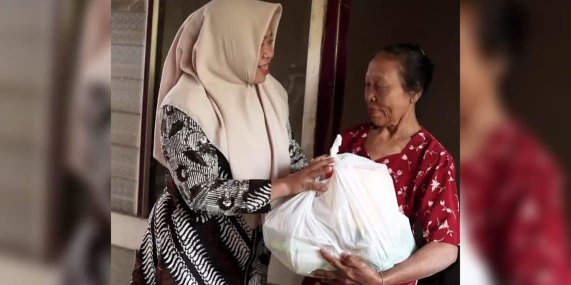 Henik Setyorini saat menyerahkan paket sembako kepada salah satu warga kurang mampu